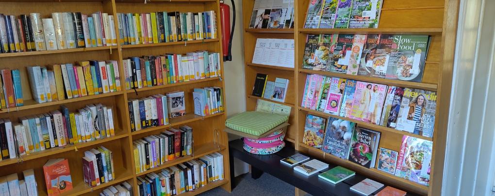 Bücherregal mit Romanen und Zeitungen