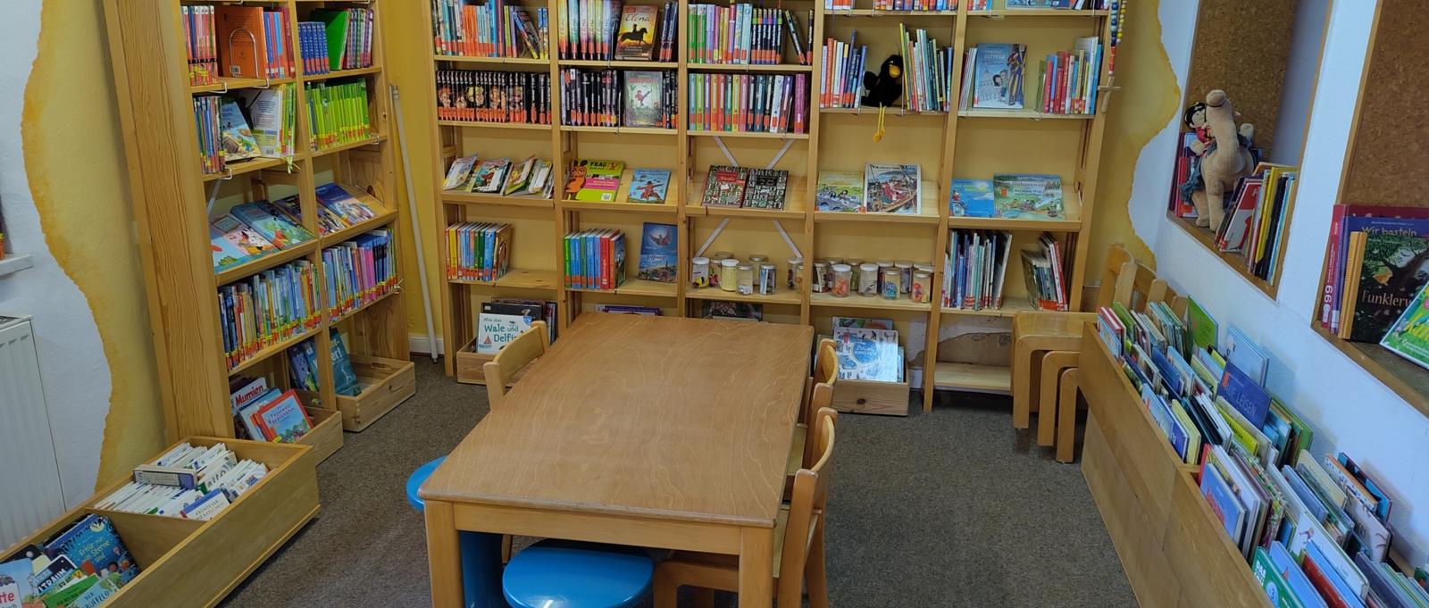 Kinderlesetisch mit Kinderbuchregalen im Hintergrund