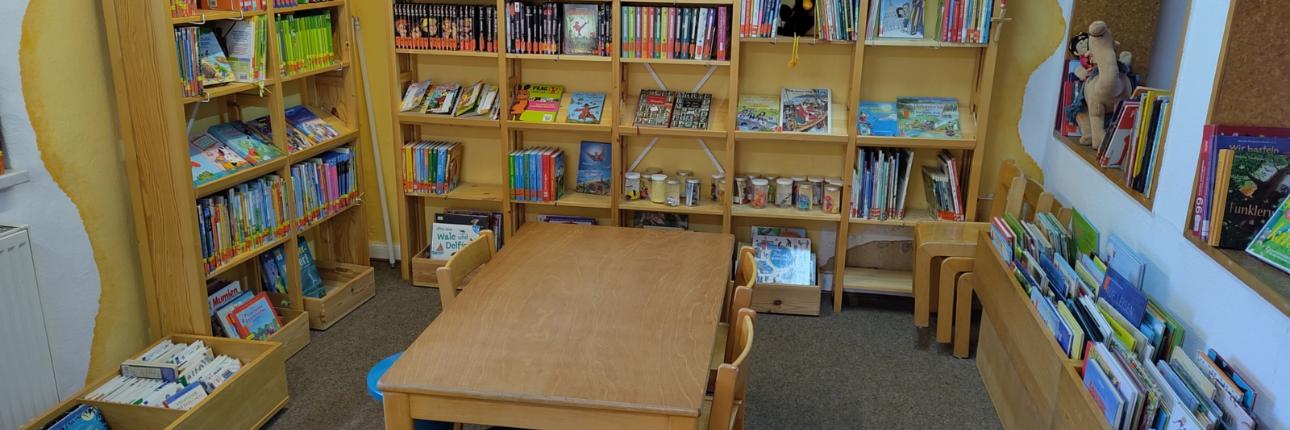 Kinderlesetisch mit Kinderbuchregalen im Hintergrund
