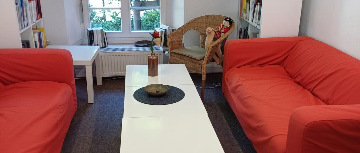 2 rote Sofas mit einem weißen Couchtisch